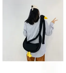 Vista posteriore della modella con borsa a tracolla in tela nera a forma di papera buffa