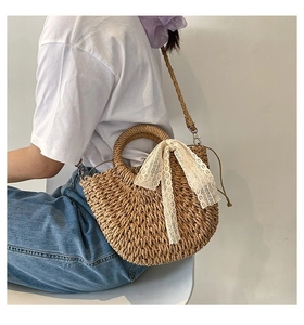 Close-up of woven straw handbag with white lace bow and round top handles