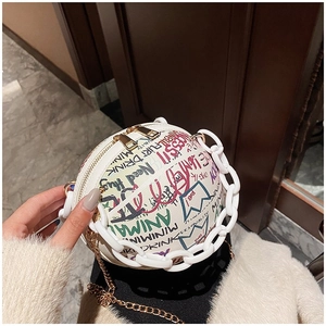 Detail of white basketball-shaped handbag featuring colorful graffiti and a chunky plastic chain