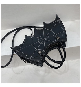 Close-up of bat-shaped handbag featuring white spider web stitching and metal zipper detail