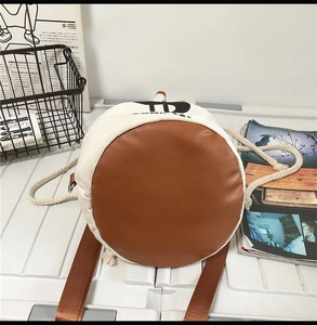Detail of color-block drawstring bag showing cream canvas and brown leather bottom