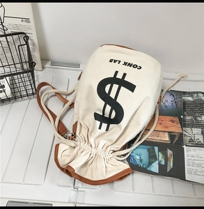 Detail of canvas drawstring bucket bag with dollar sign print and brown leather trim