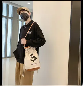 Canvas drawstring bucket bag with leather base worn by a model in a modern interior