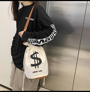 Street style canvas drawstring bucket bag with dollar sign print worn by model