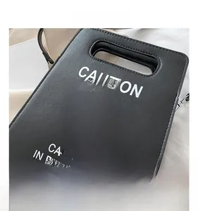 Détail du sac à bandoulière noir créatif avec logo stop et lettrage blanc caution