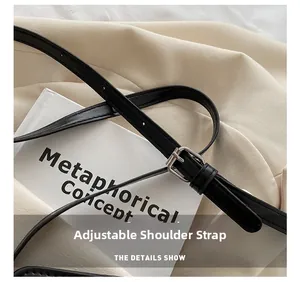 Détail d'une bandoulière réglable en cuir noir avec boucle en métal argenté sur un sac