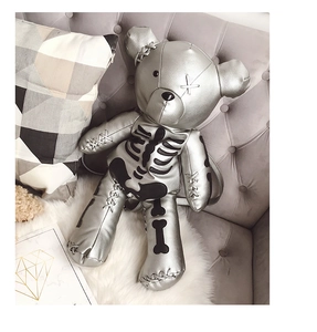 Close-up of silver PU leather bear backpack with skeleton print on a sofa