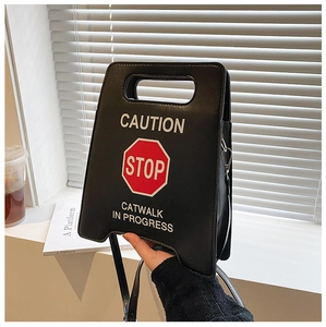 Détail d'un sac à main trapèze STOP créatif en similicuir noir au style urbain et lettrage