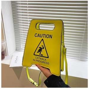 Vue détaillée du sac jaune brillant CAUTION avec l'inscription catwalk in progress