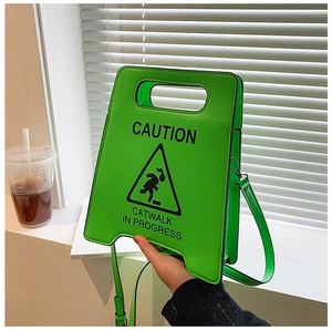 Détail du sac bandoulière vert néon en forme de panneau avec graphisme catwalk