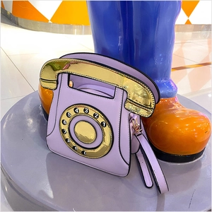 Détail d'un sac à main créatif en forme de téléphone rétro violet avec cadran doré chic