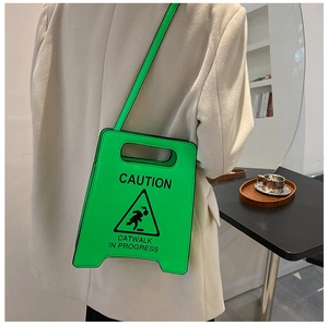 Détail du sac bandoulière vert néon style panneau Caution porté par un mannequin en café