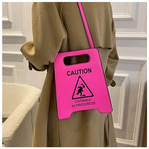 Vue arrière du mannequin portant un sac bandoulière rose néon en forme de panneau de signalisation