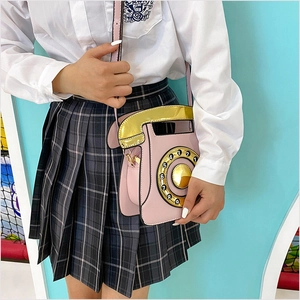 Gros plan d'un sac bandoulière téléphone rose rétro avec combiné doré et cadran rotatif
