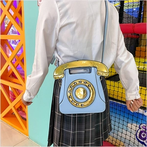 Détail du sac à bandoulière bleu en forme de téléphone avec cadran vintage et anse dorée