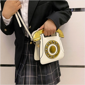 Détail d'un sac à bandoulière téléphone vintage blanc avec cadran rotatif et anse dorée