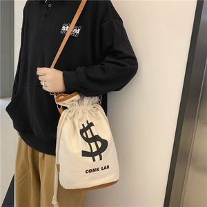Chic canvas drawstring bucket bag in off-white with brown leather trim and dollar sign