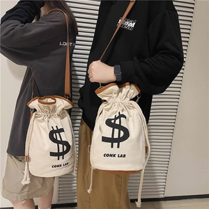 Canvas drawstring bucket bag with dollar sign print and brown leather trim for crossbody wear