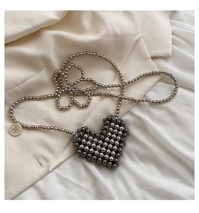 Detail of a handmade heart-shaped beaded mini bag with dark silver chain and button