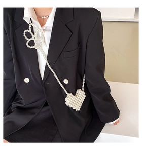 Detail of a handmade pearl heart-shaped mini bag with crossbody strap on model