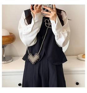 Detail of silver heart-shaped beaded mini bag with elegant crossbody chain on model
