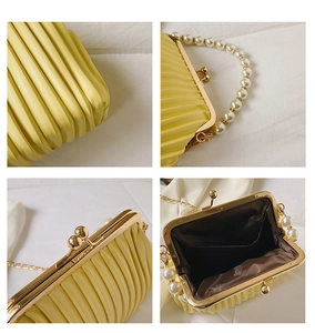 Detail view of yellow pleated evening bag with pearl handle and golden clasp