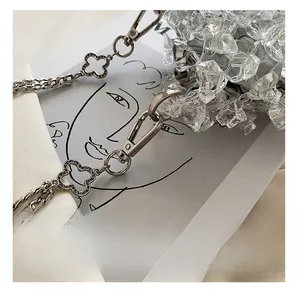 Detailed macro view of acrylic handbag featuring silver clover chain and crystal beads