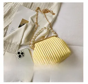Mini pleated handbag with pearl handle shown next to a smartphone for size reference
