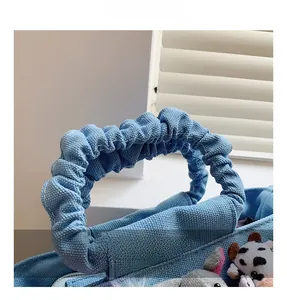 Detail of blue canvas bag featuring scrunched handles and cute plush animal charms