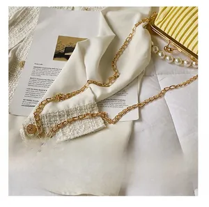 Detail of detachable golden metal chain strap on a yellow pleated shell bag