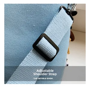 Macro detail of sky blue canvas bag with woven adjustable strap and black metal hook