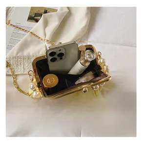 Detail showing inner capacity of yellow pleated shell bag with pearl metal frame