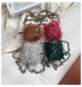 Flat lay of colorful acrylic beaded mini bags with silver chain straps on white cloth