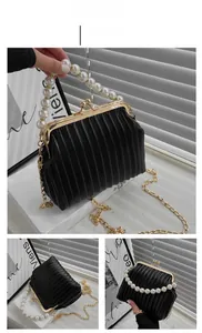 Detail of black pleated PU leather bag with large pearl handle and gold chain strap