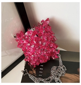 Detail of a bright pink acrylic mini chain bag with textured geometric facets