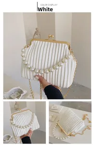 Macro detail of white pleated handbag with elegant pearl handle and golden frame