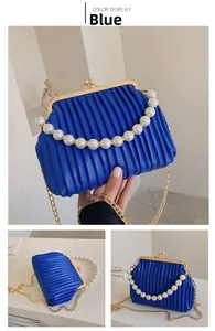 Detailed view of blue pleated shell bag with pearl handle and golden chain straps