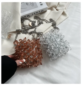 Detail of acrylic beaded crossbody bags in amber and clear colors on white fabric