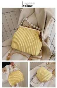 Detail of yellow pleated handbag with oversized pearl handle and gold chain strap