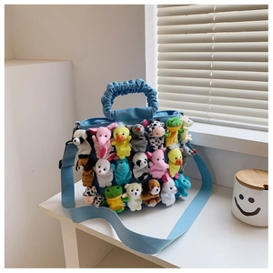 Detailed view of a blue tote bag covered in cute plush dolls and ruffled handles