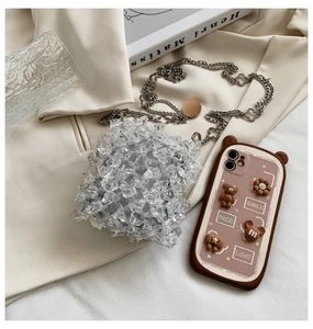 Detailed shot of transparent acrylic mini bag with silver clover chain and 3D phone case