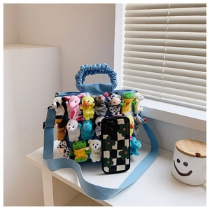 Close-up of blue denim tote bag with cute plush animal charms and pleated handles