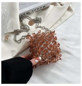 Detail of amber acrylic crystal mini bag with decorative silver clover chain strap