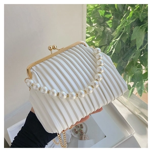 Detail of white pleated clutch with large pearl handle and elegant gold chain strap