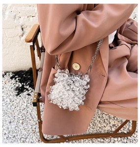 Close-up of clear acrylic crystal woven mini bag with silver chain on model's shoulder