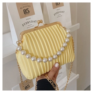 Detail of light yellow pleated handbag with large pearl handle and golden chain strap