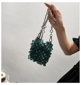 Detail of dark green acrylic beaded mini bag with silver chain and clover link