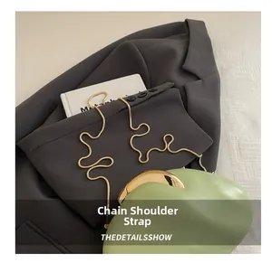 Detail of light green semi-circular bag with elegant gold snake chain strap on blazer