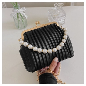 Detailed shot of black pleated shell bag with large pearl handle and gold chain strap