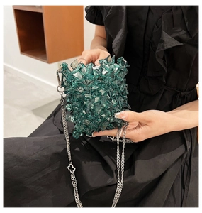 Detail of green acrylic faceted mini bag with silver chain and clover pendant charm